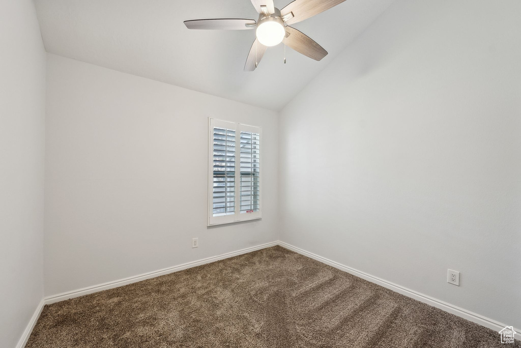Empty room with carpet floors, baseboards, ceiling fan, and vaulted ceiling