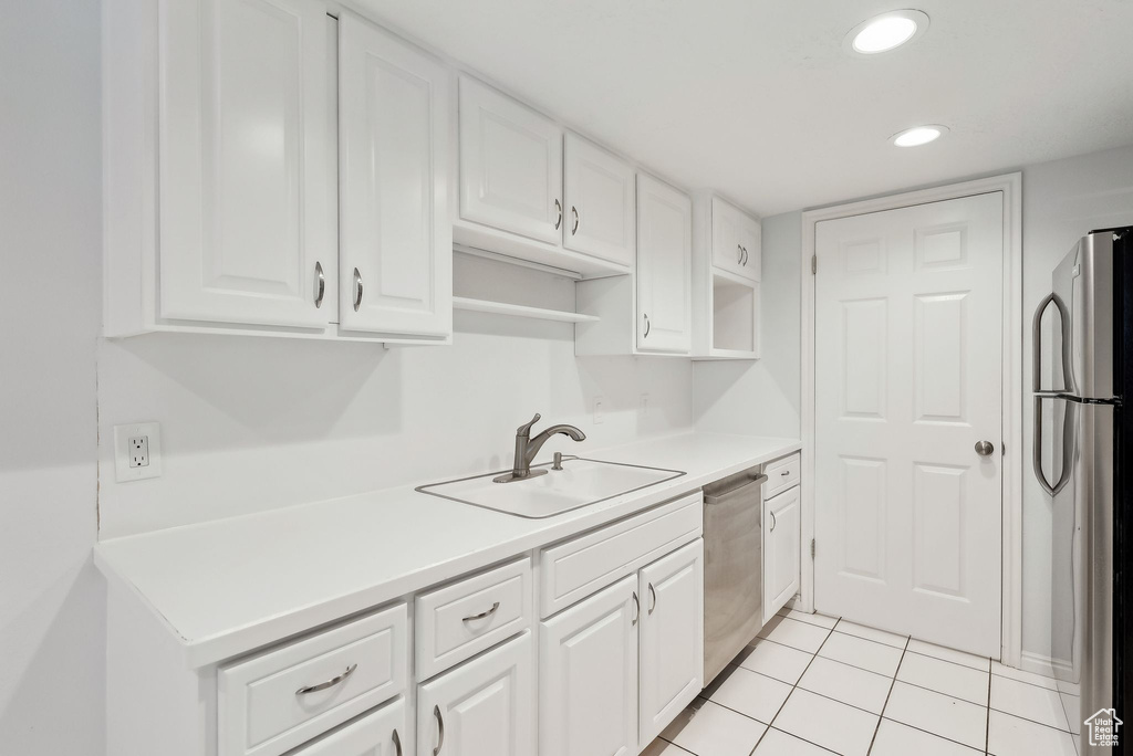 Kitchen featuring appliances with stainless steel finishes, a sink, light countertops, white cabinets, and recessed lighting