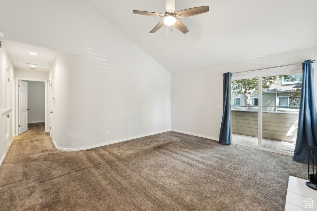 Empty room featuring ceiling fan, light colored carpet, baseboards, and lofted ceiling