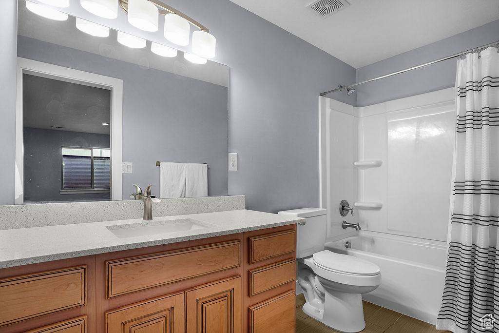 Full bath featuring visible vents, shower / bathtub combination with curtain, toilet, and vanity