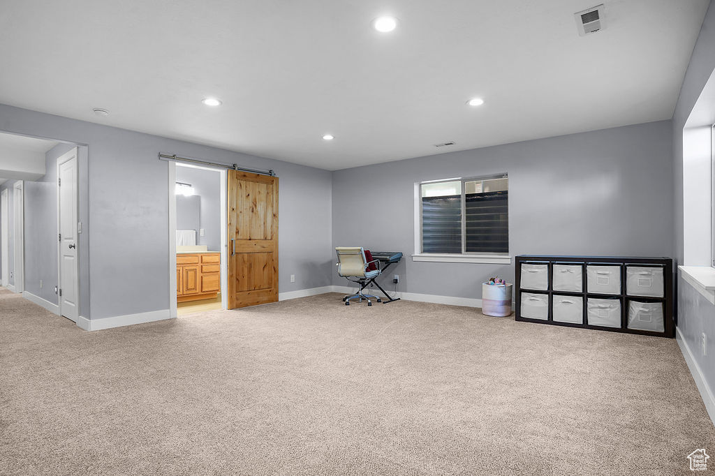 Unfurnished office featuring visible vents, a barn door, and carpet
