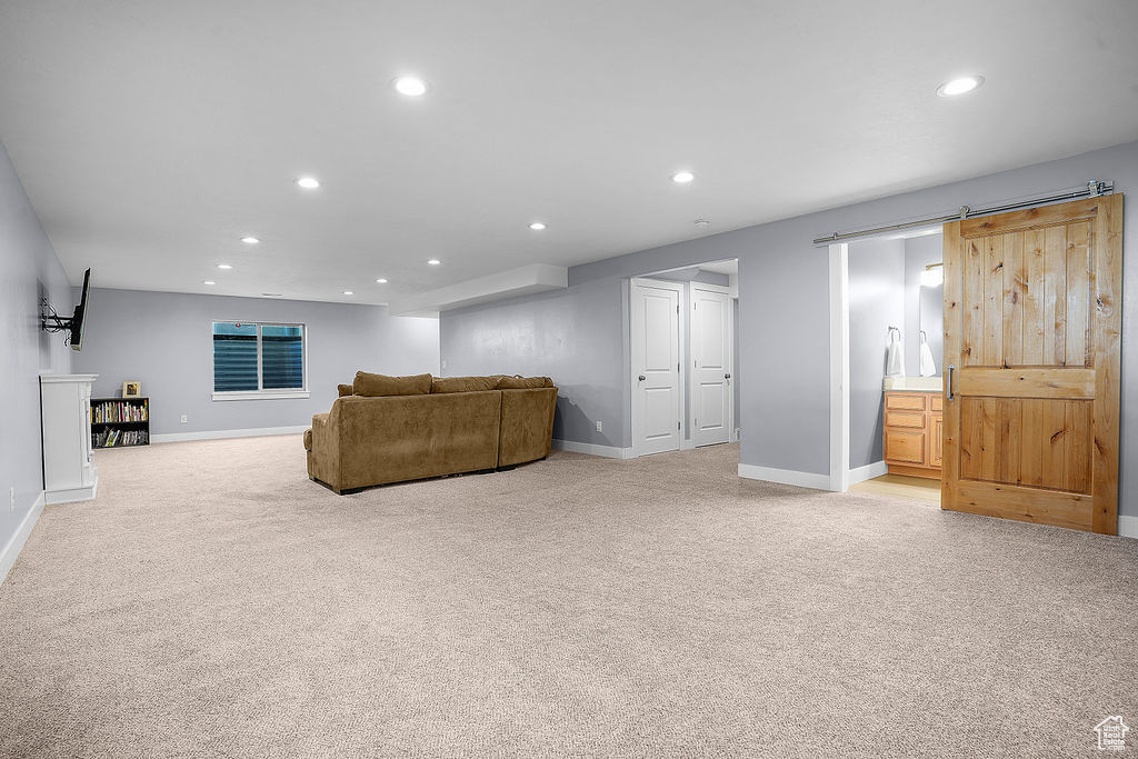 Carpeted living room with recessed lighting, a barn door, and baseboards