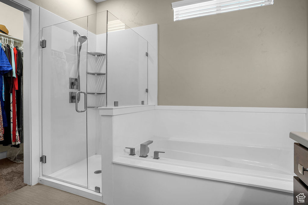 Full bath featuring a garden tub, a walk in closet, and a shower stall