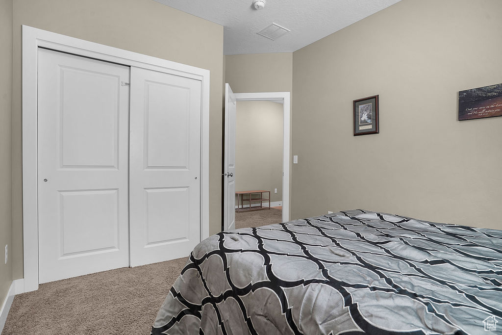 Carpeted bedroom featuring a closet and baseboards