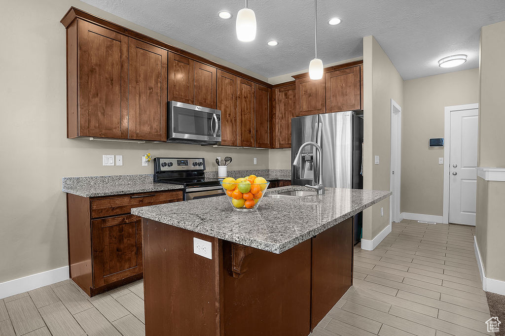 Kitchen featuring a sink, baseboards, light stone countertops, and stainless steel appliances