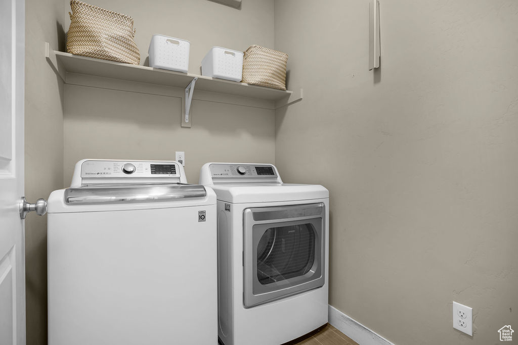 Clothes washing area featuring laundry area, baseboards, and washing machine and clothes dryer