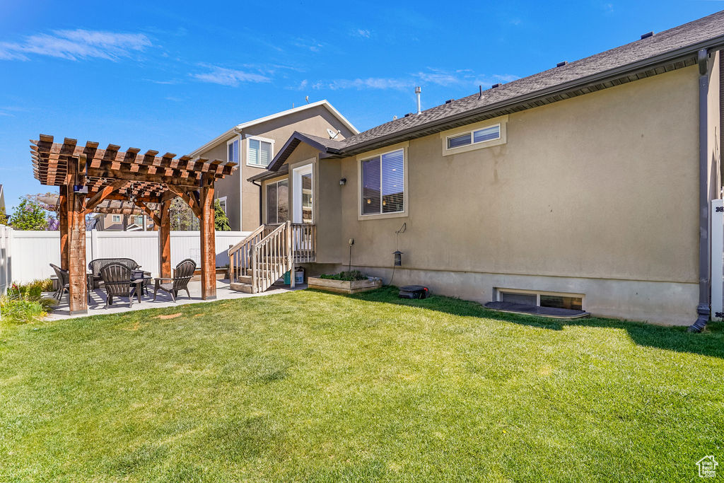 Back of house featuring fence, a pergola, stucco siding, a patio area, and a yard