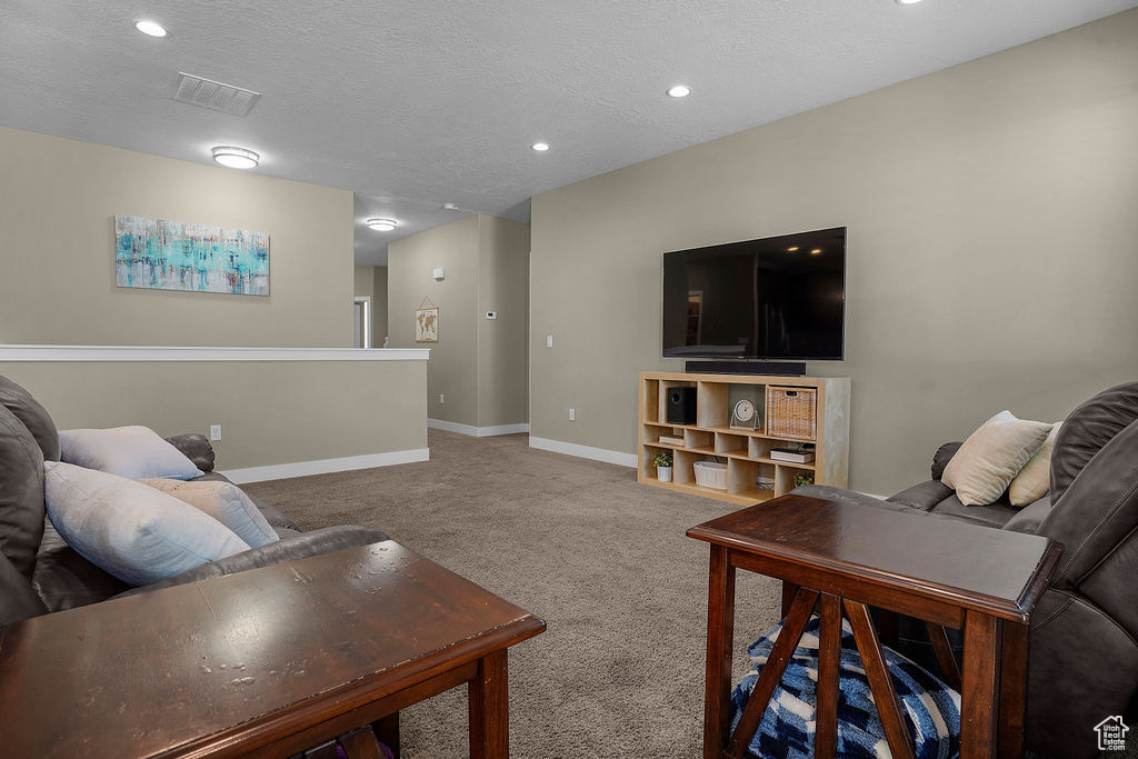 Living area featuring a textured ceiling, visible vents, carpet floors, baseboards, and recessed lighting