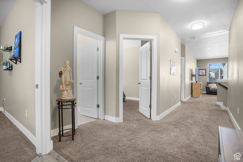 Hallway with baseboards and light colored carpet