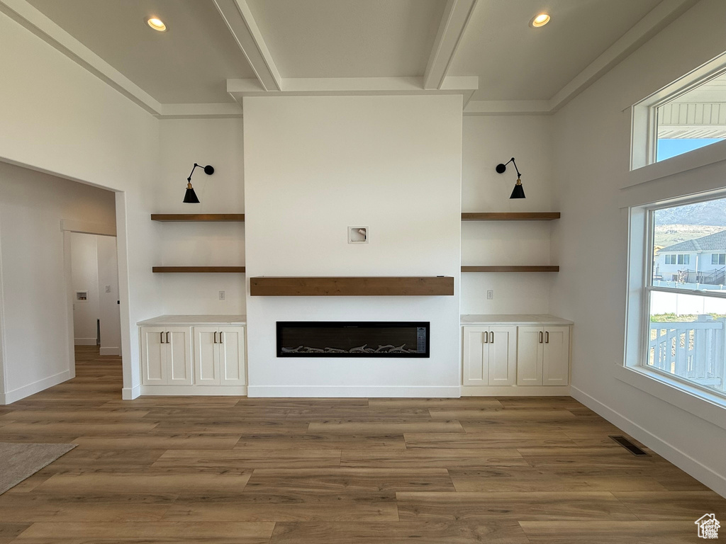 Unfurnished living room with a glass covered fireplace, plenty of natural light, and built in shelves
