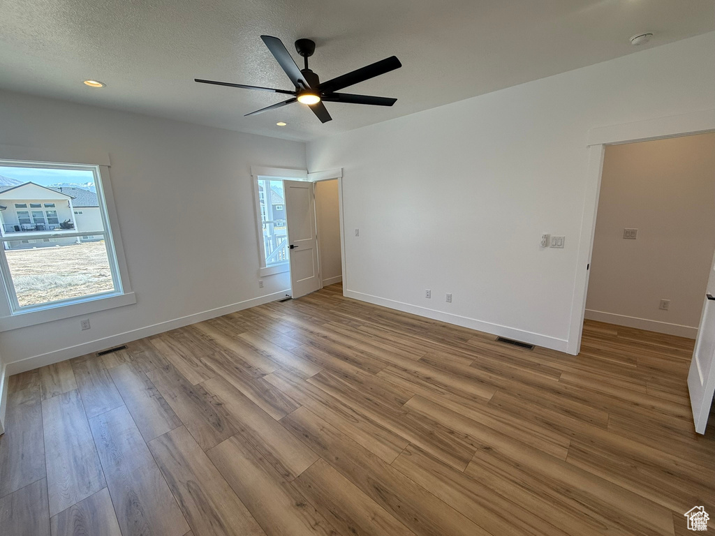 Empty room featuring baseboards, ceiling fan, visible vents, and wood finished floors