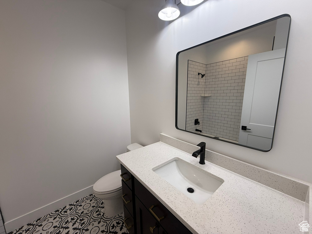 Bathroom featuring vanity, walk in shower, tile patterned floors, and toilet