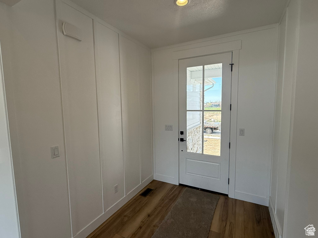 Doorway with baseboards, wood finished floors, and visible vents