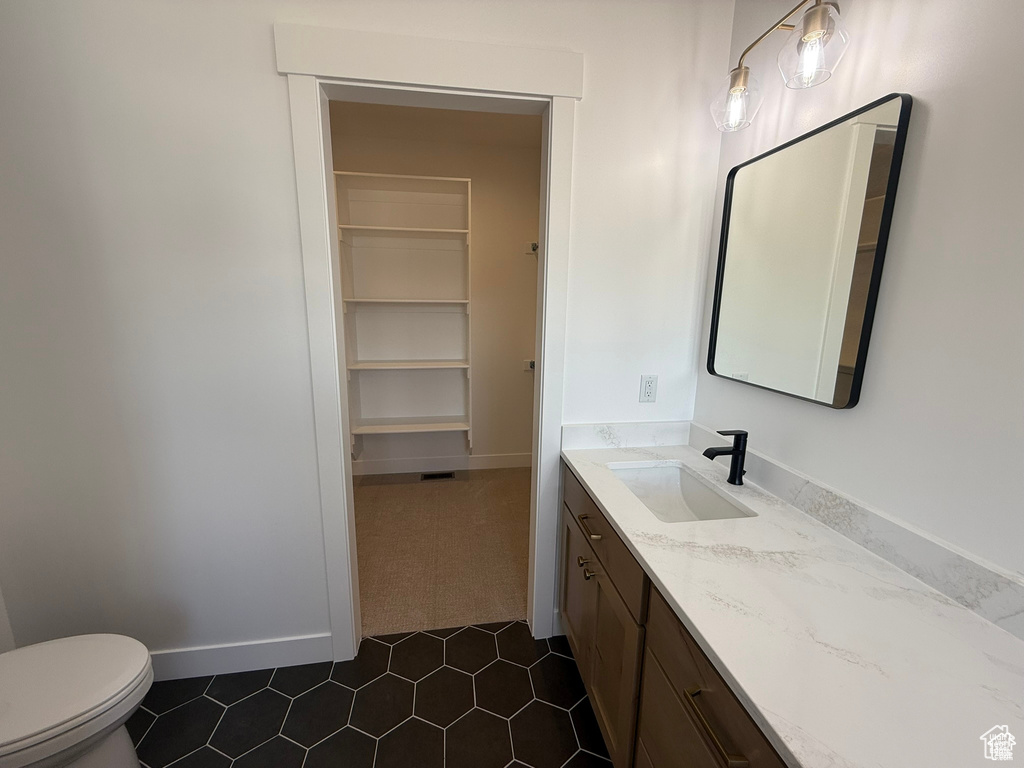 Bathroom with vanity, tile patterned floors, baseboards, and toilet