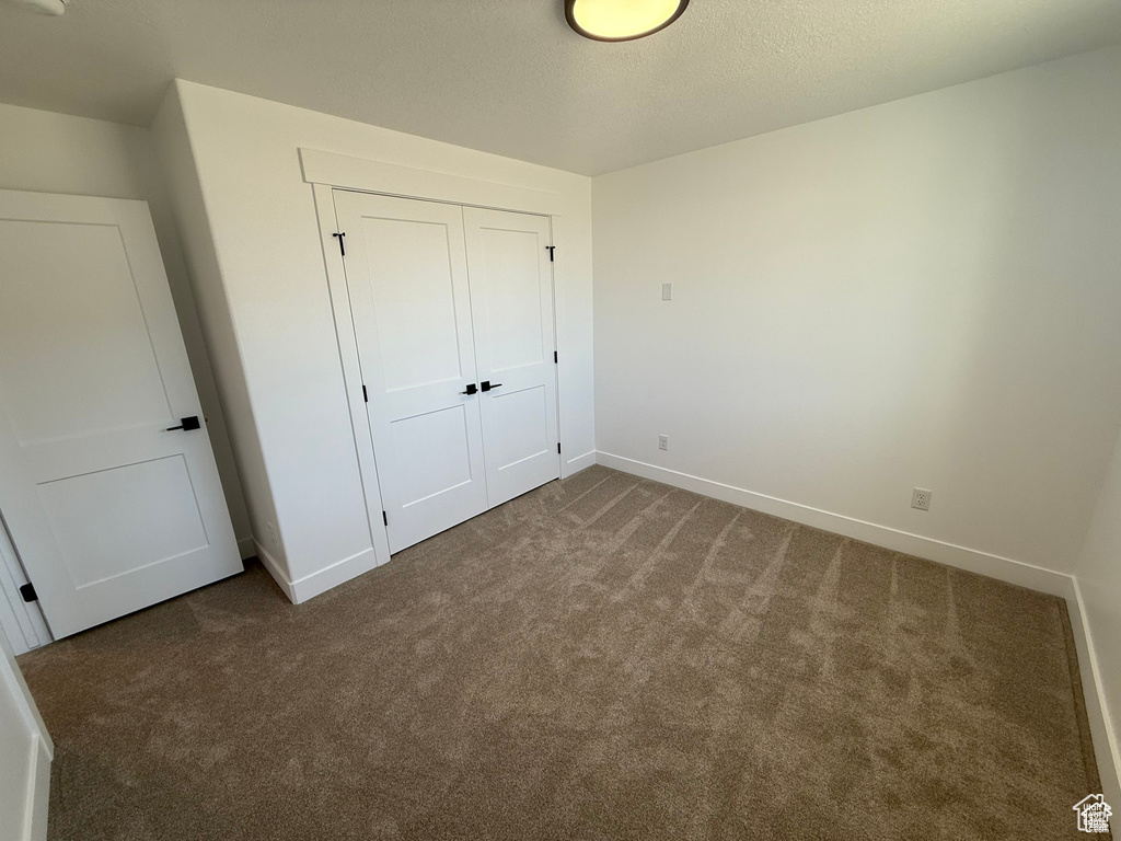 Unfurnished bedroom with carpet floors, baseboards, and a closet