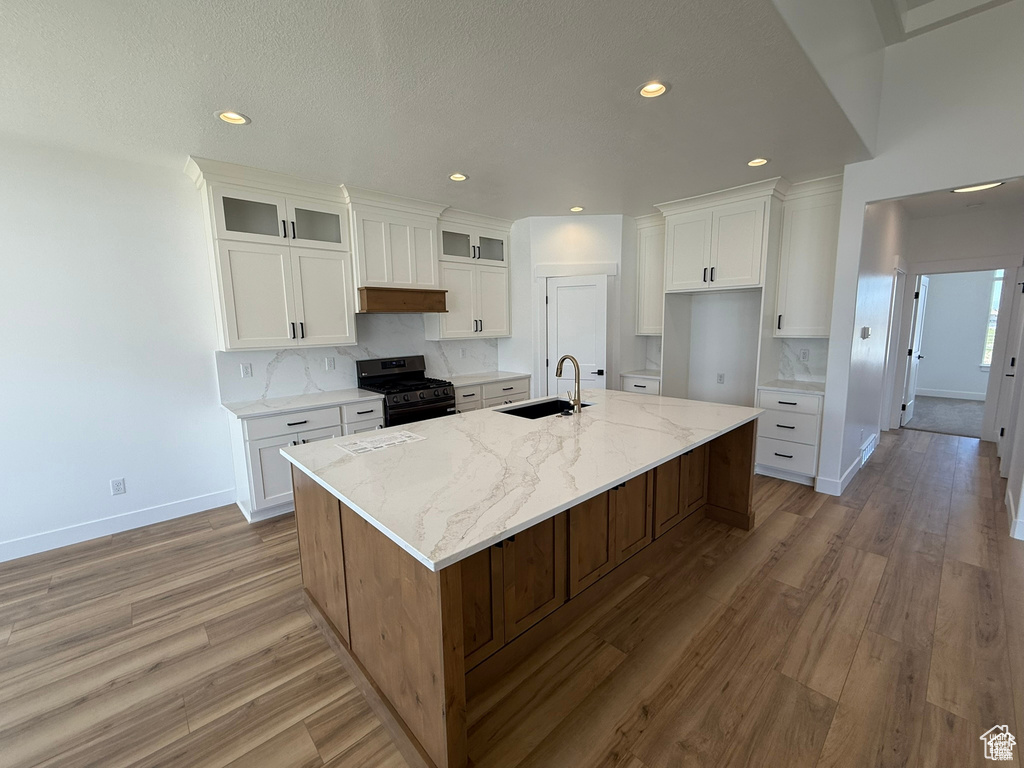 Kitchen with baseboards, a sink, gas stove, and light wood-style floors