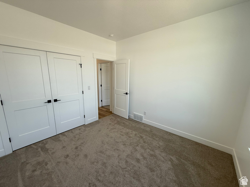 Unfurnished bedroom featuring baseboards, carpet, a closet, and visible vents