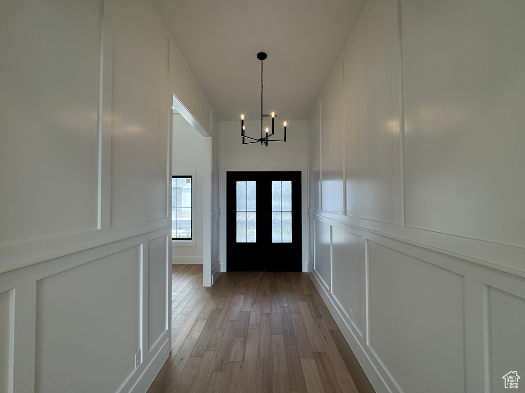 Entryway with wood finished floors, a decorative wall, and a notable chandelier