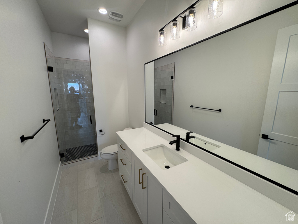 Full bathroom with vanity, toilet, baseboards, a shower stall, and visible vents