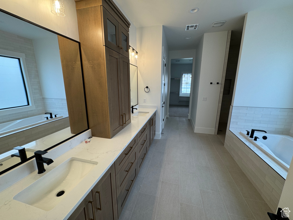 Bathroom featuring double vanity, a bath, visible vents, a sink, and tile patterned floors