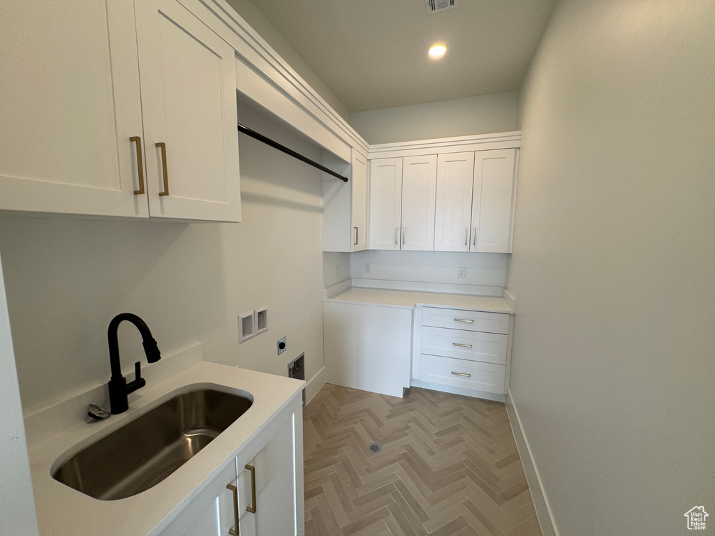 Clothes washing area featuring baseboards, cabinet space, electric dryer hookup, a sink, and washer hookup