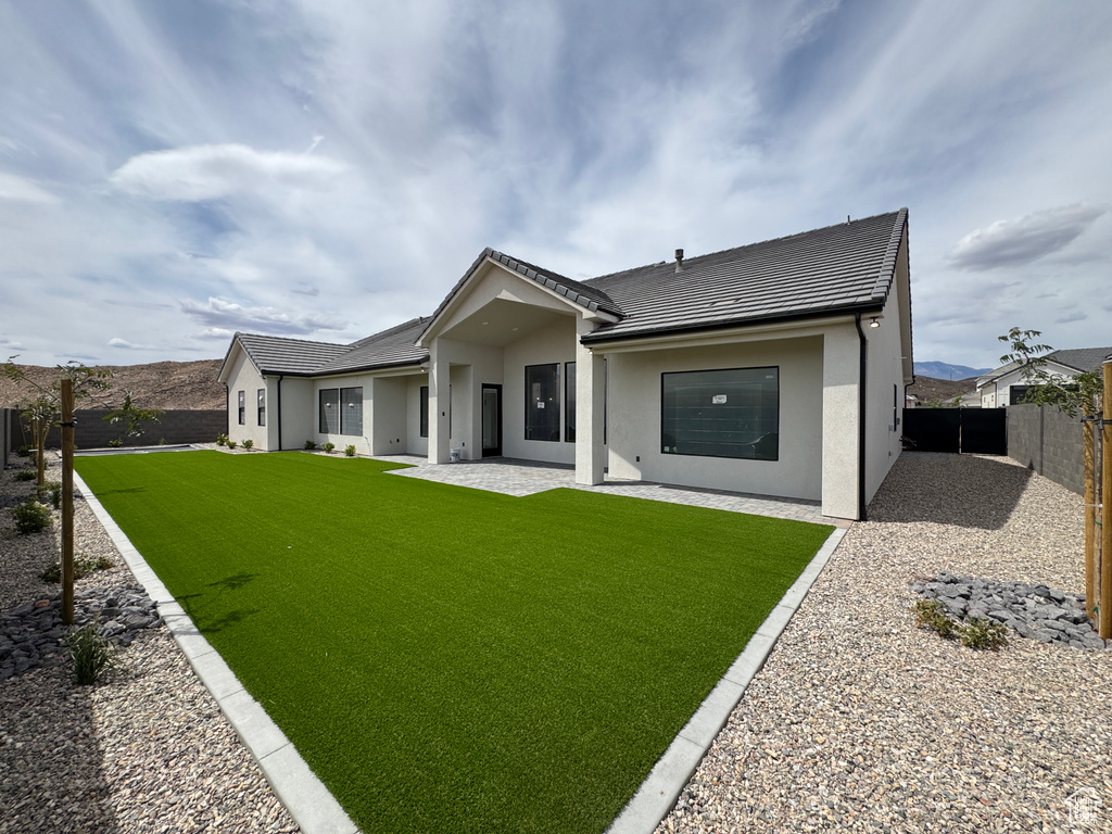 Rear view of house featuring a tiled roof, a yard, a fenced backyard, and stucco siding