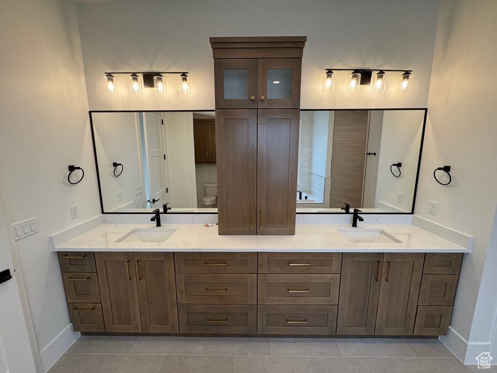 Bathroom with a sink, baseboards, tile patterned floors, and double vanity
