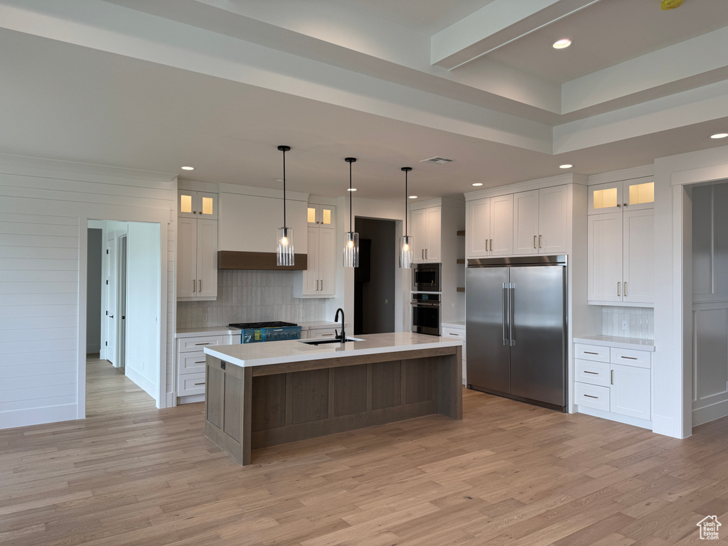 Kitchen with built in appliances, decorative backsplash, a sink, and light countertops