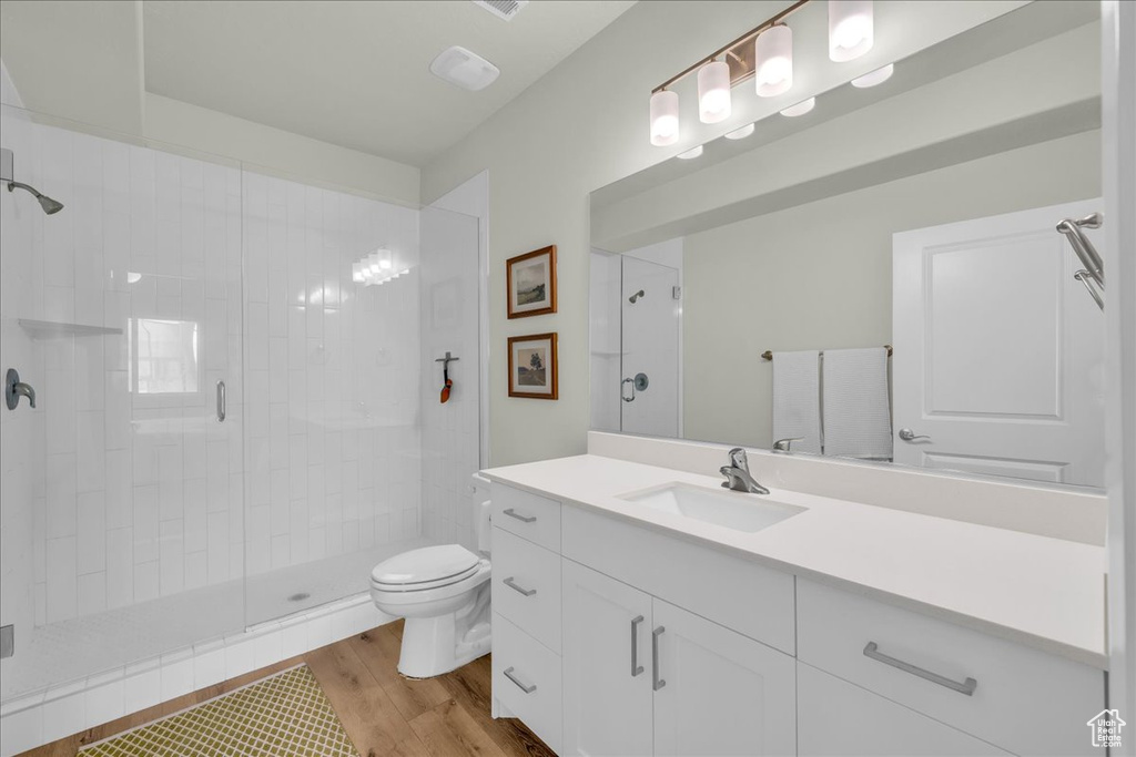 Bathroom with toilet, a shower stall, wood finished floors, and vanity