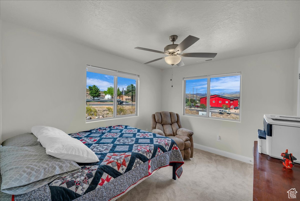 Bedroom featuring carpet flooring, a textured ceiling, baseboards, and ceiling fan