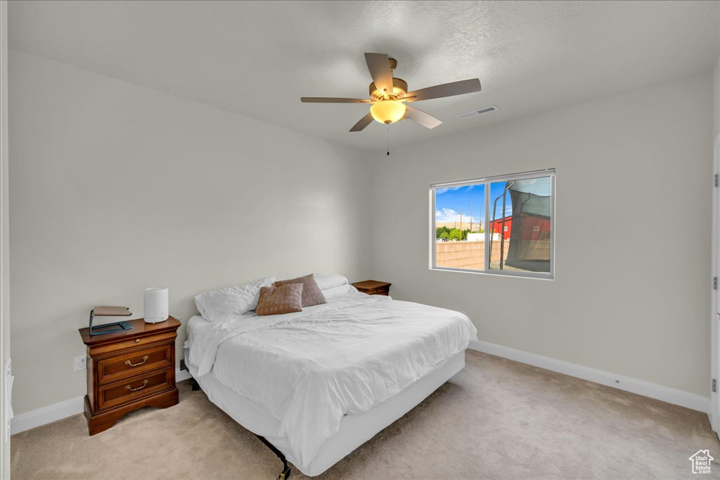Bedroom with baseboards, ceiling fan, light carpet, and visible vents