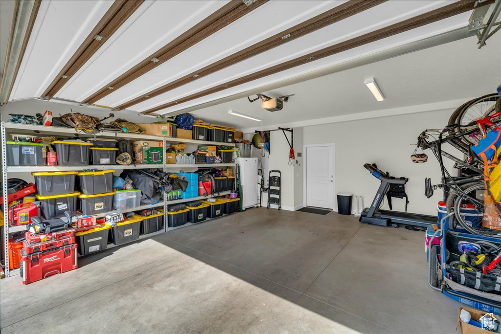 Garage featuring a garage door opener and white refrigerator