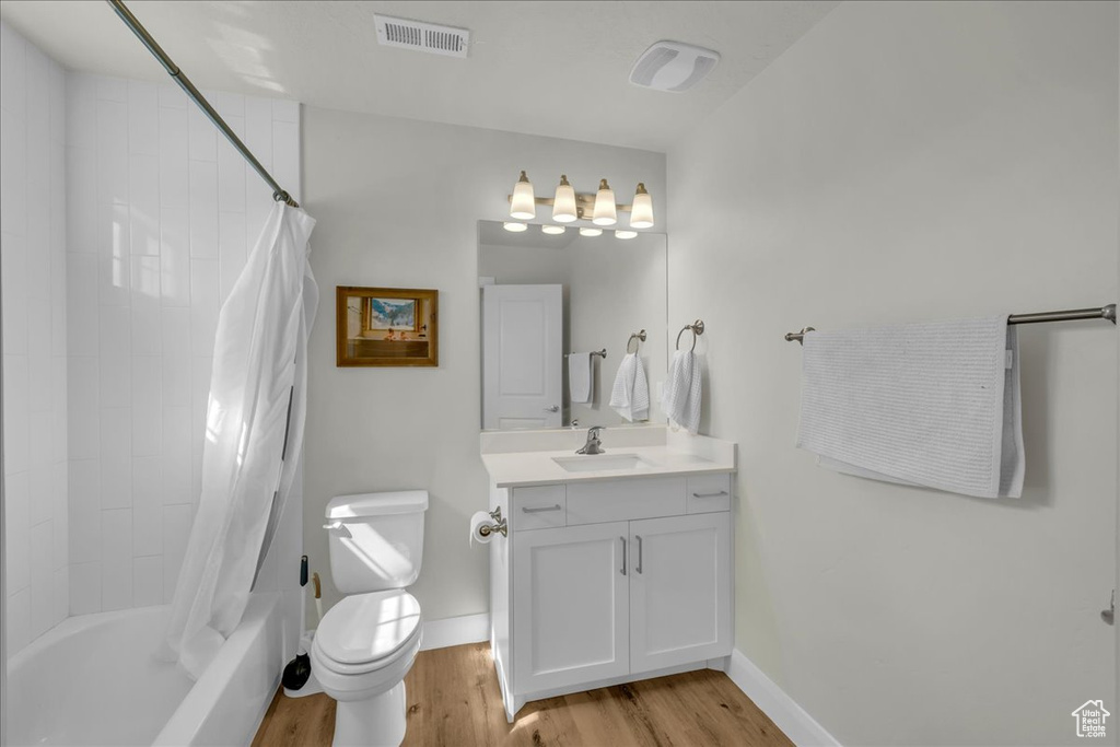 Bathroom with visible vents, vanity, wood finished floors, toilet, and baseboards