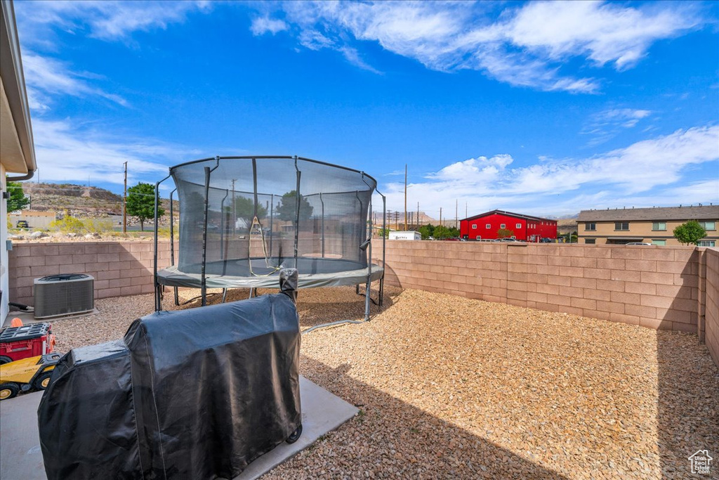 View of yard with central air condition unit, a trampoline, and a fenced backyard