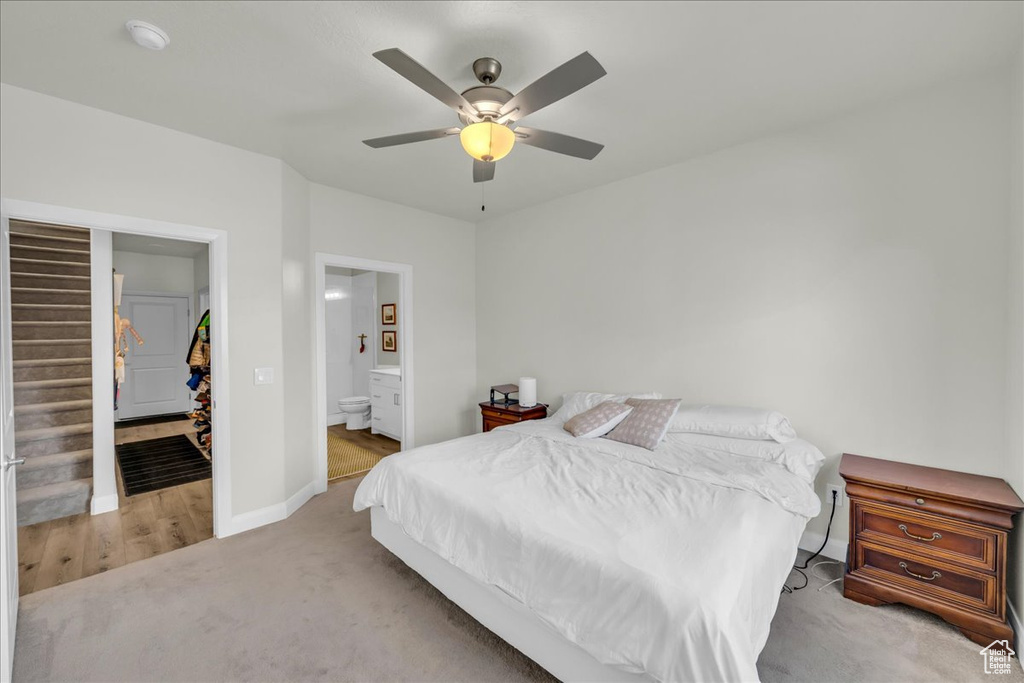 Carpeted bedroom with baseboards, a ceiling fan, ensuite bathroom, and a spacious closet
