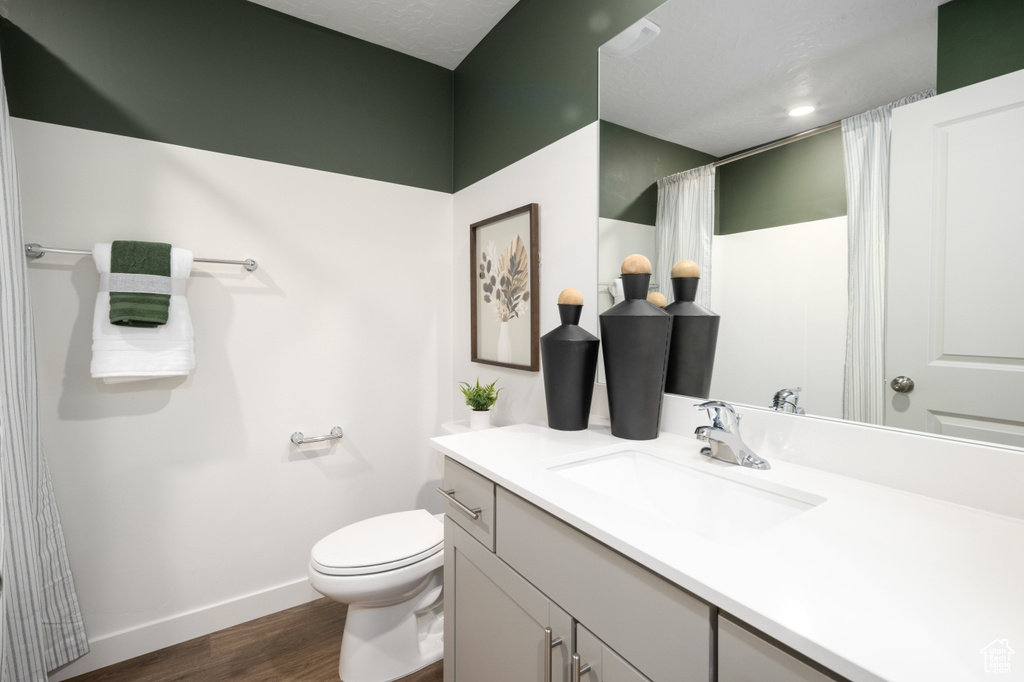 Bathroom featuring vanity, toilet, a shower with shower curtain, baseboards, and wood finished floors