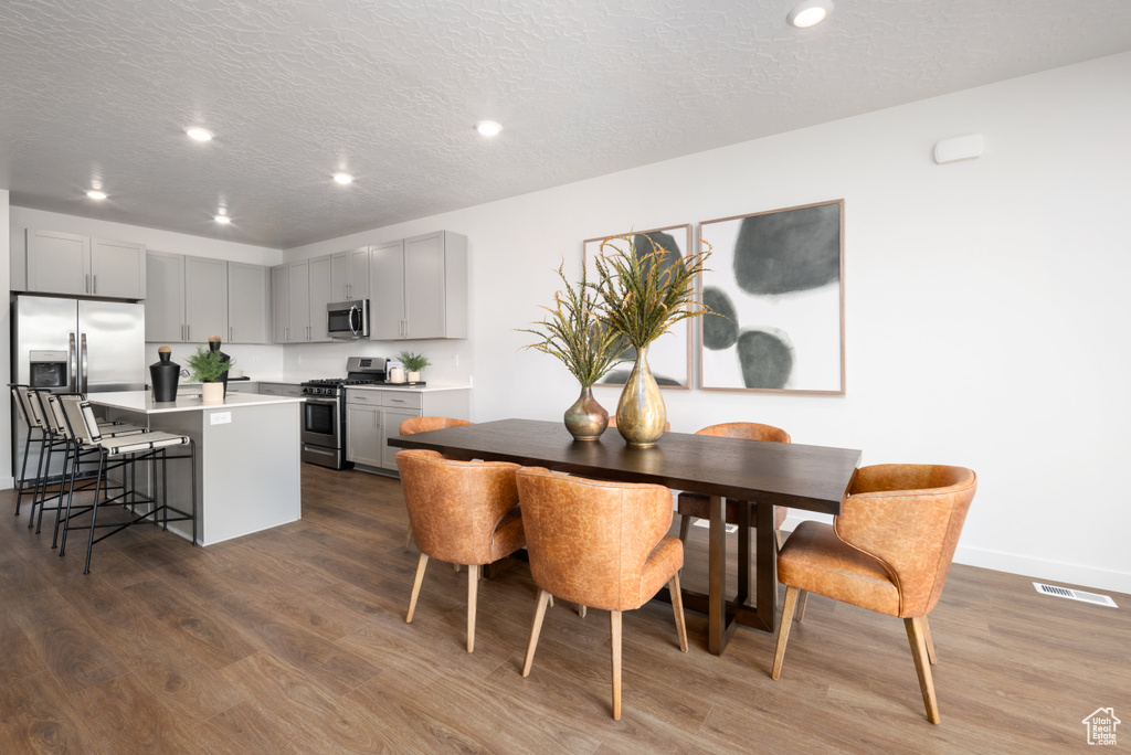 Dining space featuring a textured ceiling, visible vents, dark wood finished floors, baseboards, and recessed lighting