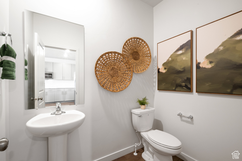 Bathroom with toilet, baseboards, a sink, and wood finished floors