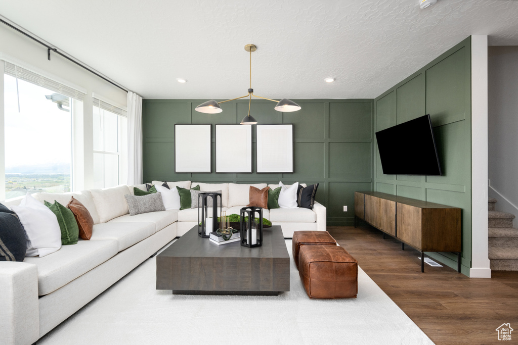 Living room featuring recessed lighting, a decorative wall, dark wood-style floors, and stairway