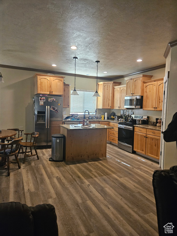 Kitchen with ornamental molding, a kitchen island, dark wood-style floors, a textured ceiling, and stainless steel appliances