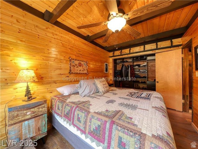Bedroom featuring wood ceiling, wood walls, beam ceiling, and wood finished floors