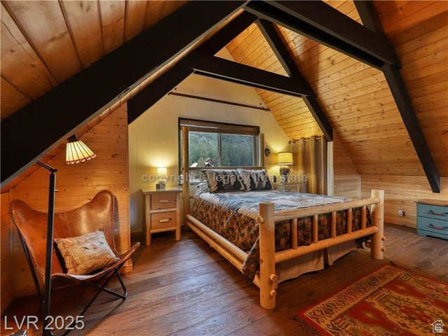 Bedroom with wood ceiling, vaulted ceiling with beams, wood-type flooring, and wood walls