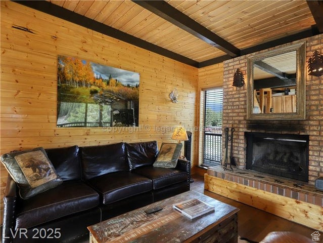 Living room featuring wood ceiling, wood walls, beam ceiling, and a fireplace