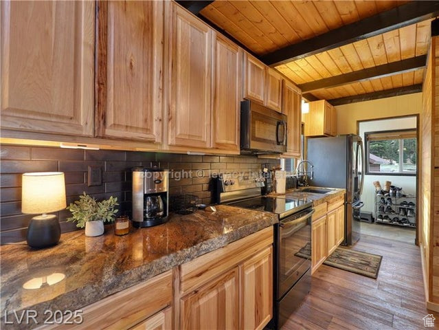 Kitchen featuring beam ceiling, decorative backsplash, wooden ceiling, wood finished floors, and range with electric stovetop
