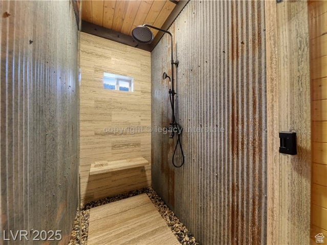 Full bath featuring wooden walls, a tile shower, and wood ceiling