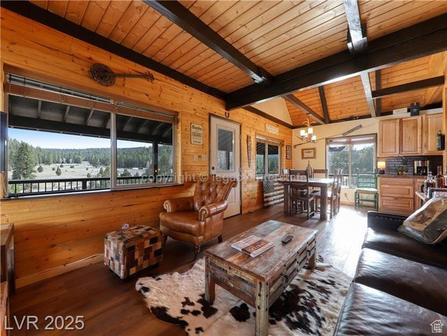 Living area featuring wooden walls, wooden ceiling, wood-type flooring, and a notable chandelier
