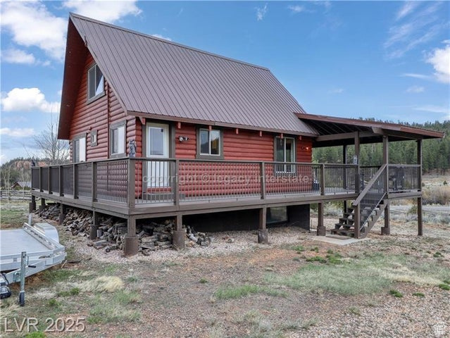 Rear view of house with log veneer siding, metal roof, a deck, and stairway