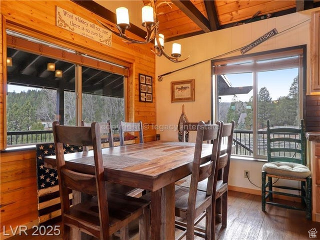 Dining area with wood-type flooring, a notable chandelier, and a healthy amount of sunlight