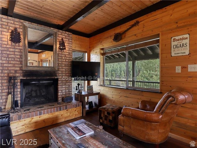 Living area featuring a brick fireplace, wood finished floors, beamed ceiling, wooden walls, and wood ceiling