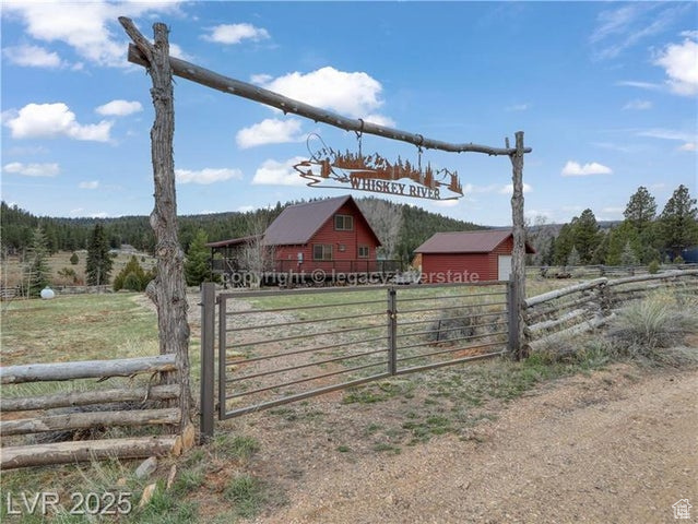 View of gate with fence, an outdoor structure, and a rural view